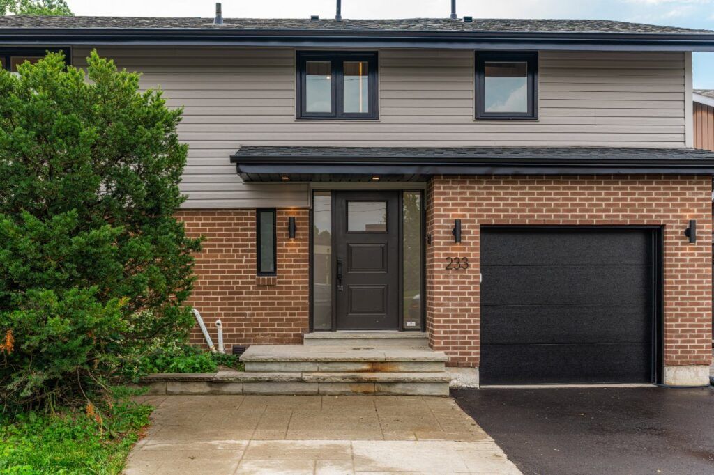 Front entry of a renovated Scarborough home with a black door and new garage door