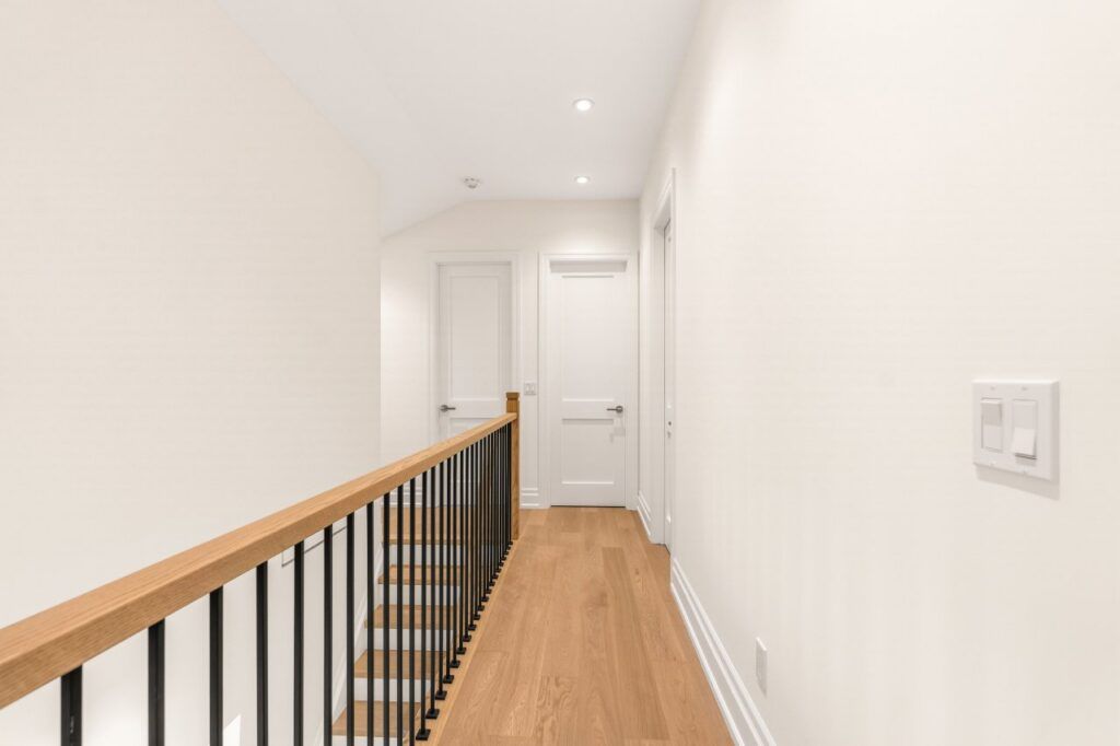 Upper hallway with white oak flooring and an open-riser staircase with black railing